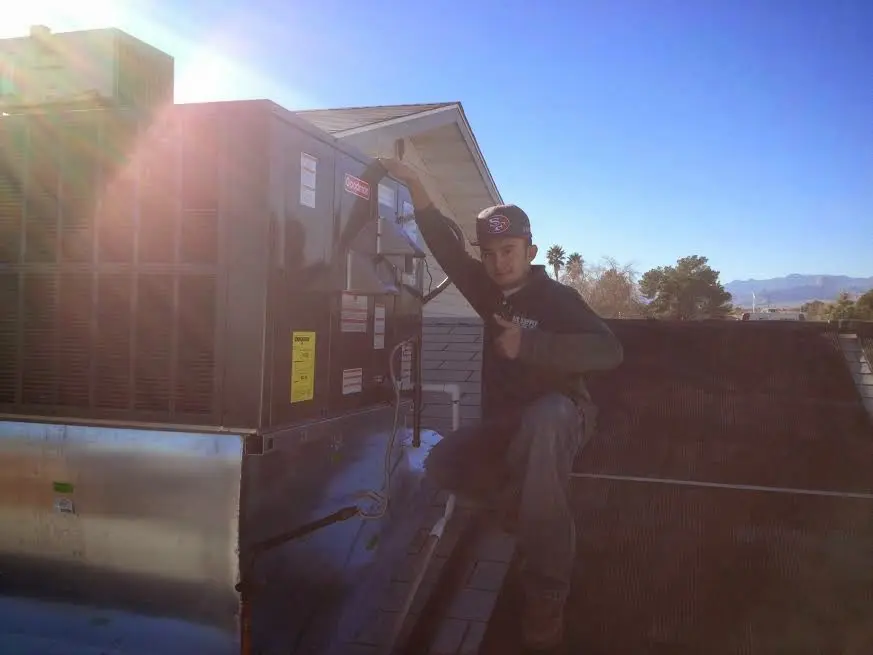 HVAC technician performing Air Duct Cleaning on a rooftop unit in Hurricane